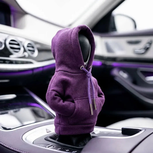 Funda tipo buzo para palanca de cambios de carro en tela suave, con capucha decorativa, cordones y diseño original para proteger y personalizar el vehículo.