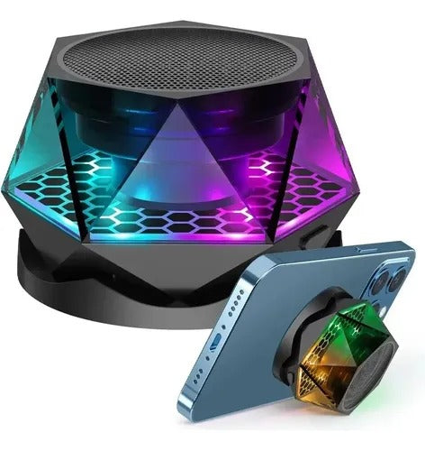 Parlante Bluetooth magnético hexagonal con luz LED multicolor, Bluetooth 5.3, función TWS, base compatible con MagSafe y soporte para celular. Incluye anillo adhesivo y cable de carga.