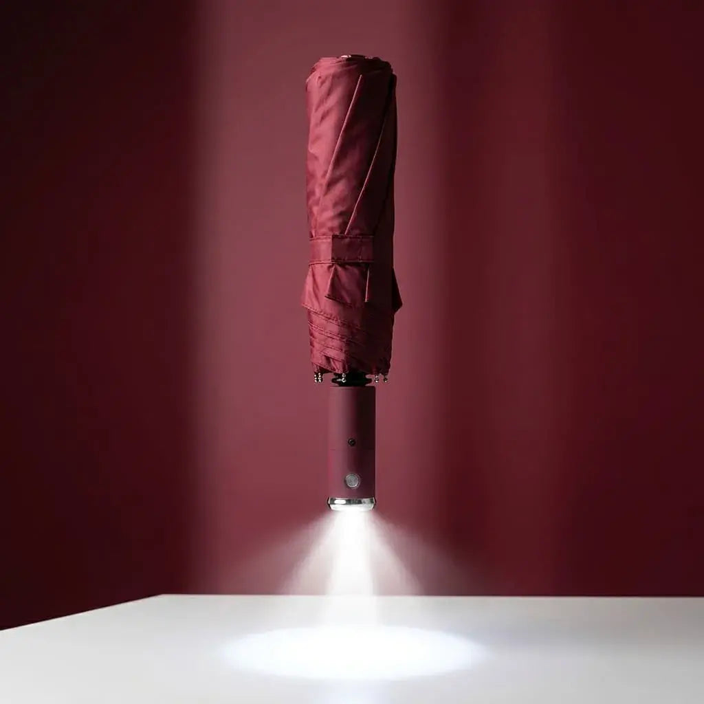 Sombrilla compacta con linterna LED integrada, tela impermeable, mango ergonómico y estructura reforzada. Ideal para lluvia, noche, viajes y uso diario.