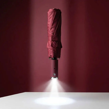 Sombrilla compacta con linterna LED integrada, tela impermeable, mango ergonómico y estructura reforzada. Ideal para lluvia, noche, viajes y uso diario.